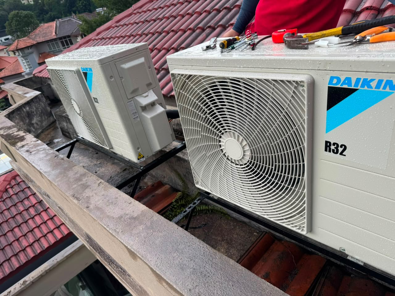 Dua unit outdoor aircond baru dipasang pada braket di sebelah genting bumbung